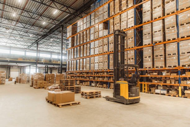 Warehouse worker retrieving inventory from tall storage shelving, representing warehousing and distribution